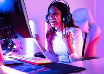 Headset Gamer Barato: Os 12 melhores Atualmente 23 Gamer feliz usando um headset gamer barato em um setup colorido.