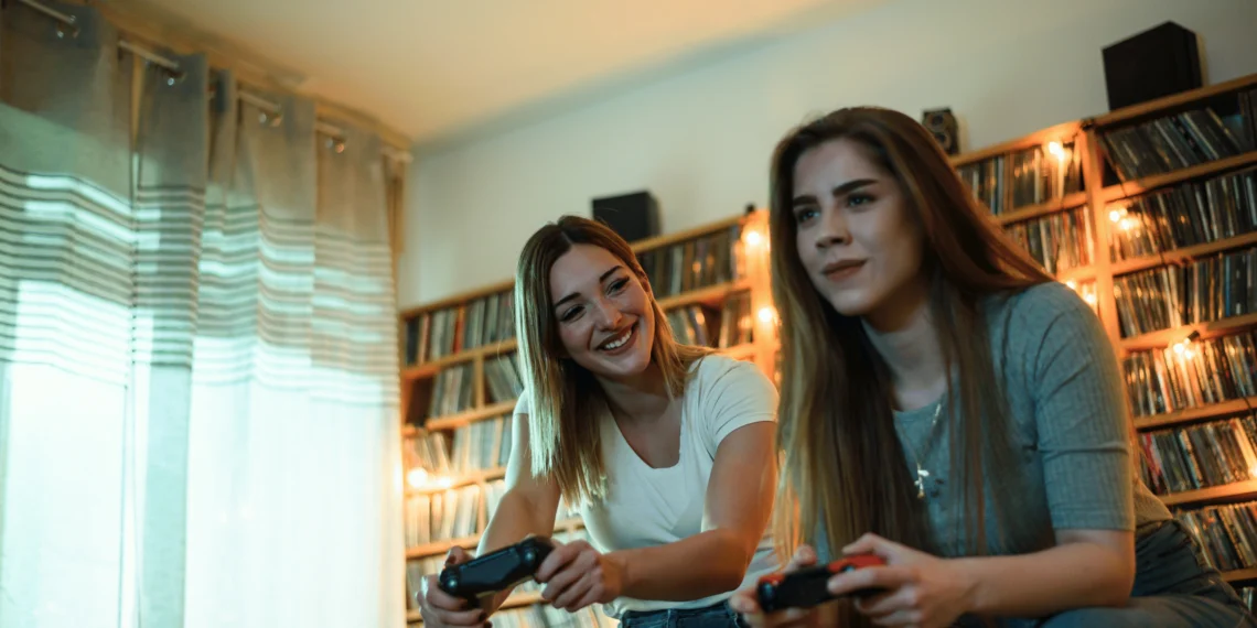 Os 25 melhores jogos de videogame da história 1 Duas mulheres jogando videogame em um ambiente aconchegante, destacando os melhores jogos de videogame.