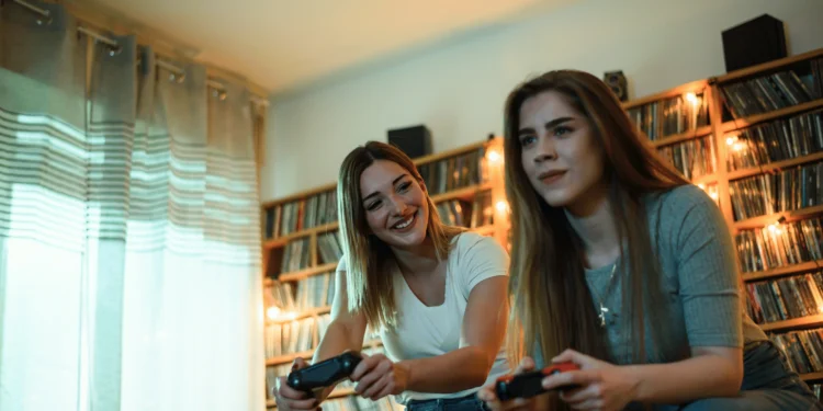 Os 25 melhores jogos de videogame da história 5 Duas mulheres jogando videogame em um ambiente aconchegante, destacando os melhores jogos de videogame.