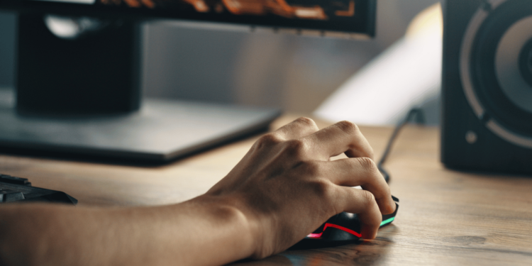 Mão segurando um mouse em uma mesa gamer de alta qualidade.