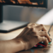 As 10 Melhores Mesas Gamer Atualmente! 1 Mão segurando um mouse em uma mesa gamer de alta qualidade.
