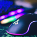 Imagem de uns dos Melhores Mouses Gamer sem Fio com iluminação RGB, destacado em um ambiente de jogo com um teclado RGB ao fundo.
