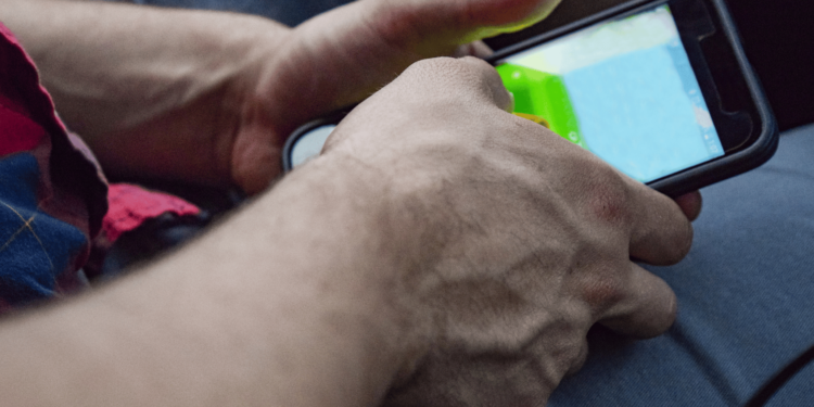 Mãos de um jogador segurando um celular enquanto joga.