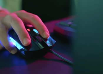 Imagem de um mouse gamer barato até 150 reais com iluminação LED, sendo utilizado em um ambiente de jogo, destacando seu design ergonômico e acessível.