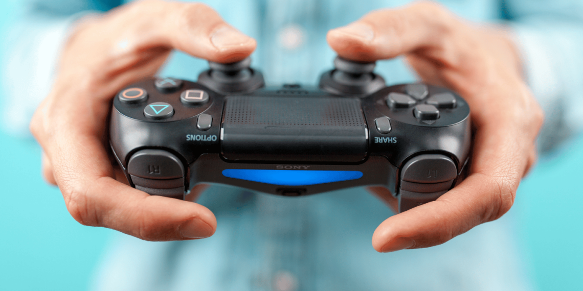 Como Jogar Com controle de PS4 no PC, Veja agora! 1 Mãos segurando um controle de PS4, com um fundo azul claro, pronto para jogar no PC.