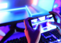 20 Melhores Jogos para Android em 2024 11 Jogador interagindo com um jogo no celular enquanto o PC está ao fundo, representando a evolução dos jogos mobile em 2024.