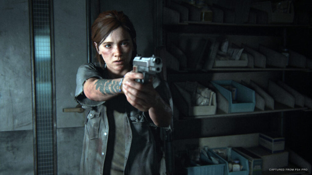 Ellie aponta uma arma com uma expressão séria em The Last of Us Part II, dentro de um local abandonado.